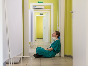 Tired nurse sitting by the hallway