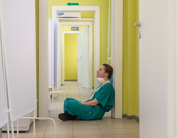 Exhausted nurse sitting by the hallway